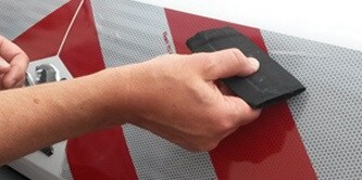 Person applying vehicle warning chevron markings to a van
