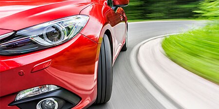 Car turning around a bend installed with red 3M Vehicle wraps and trims.
