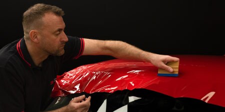 Man installing 3M Graphic Films using proper Film installation Tools 

