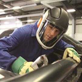Worker in protective coveralls and powered and supplied air mask