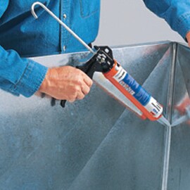 Adhesive or sealant being applied over seam in metal sheet