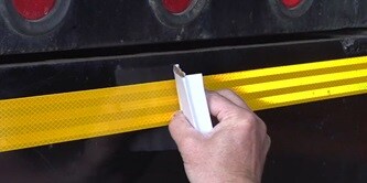 Person applying conspicuity tape to a truck
