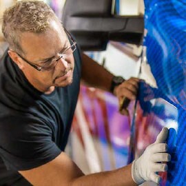Man installing blue 3M Graphic Films on to a car
