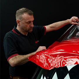 Man installing 3M Car Wrap to front of car