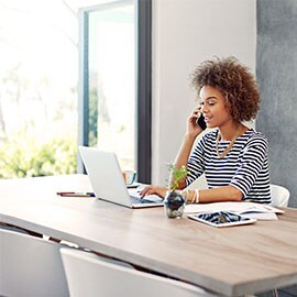 Woman sitting at desk with laptop in front of her. Door out to the garden is open.