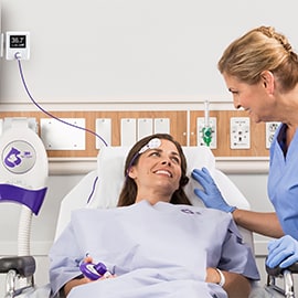 A nurse checks on a patient laying in a hospital bed